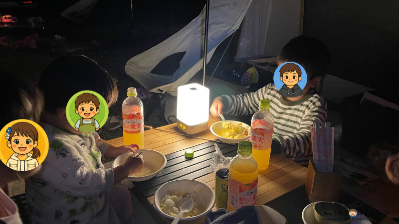 秋キャンプでランタンを囲んで家族で夕食を食べる様子