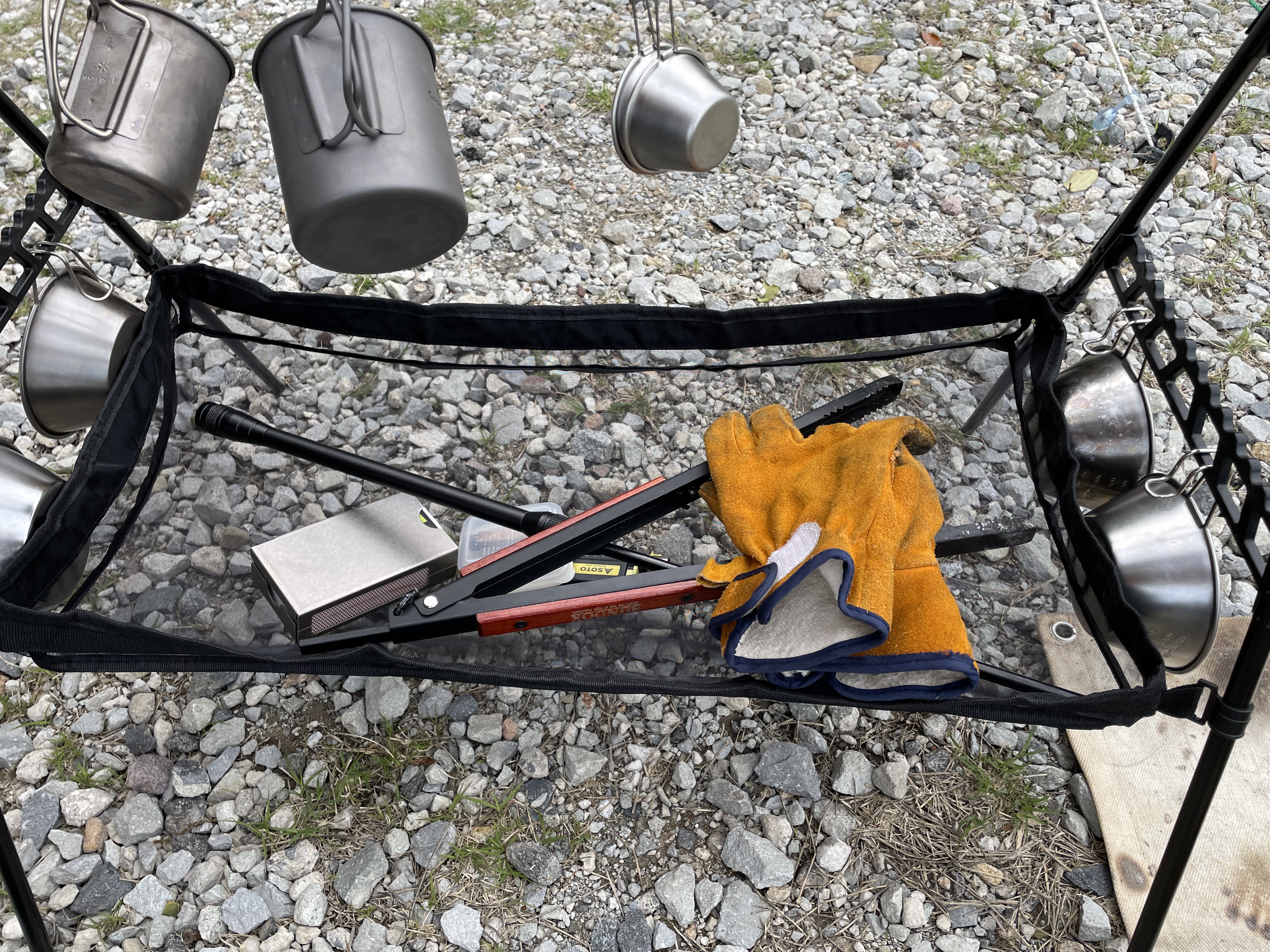 ダイソーのハンギングラックにメッシュネットを装着して火吹き棒やライターを収納している様子