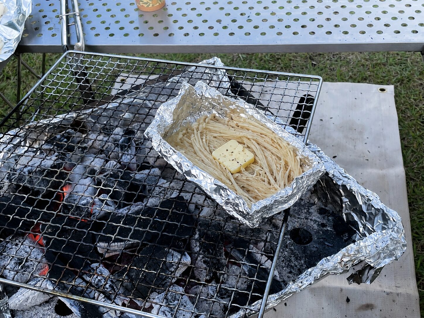 ユニフレーム ファイアグリルでえのきのバターホイル焼きを作っているキャンプ料理の様子